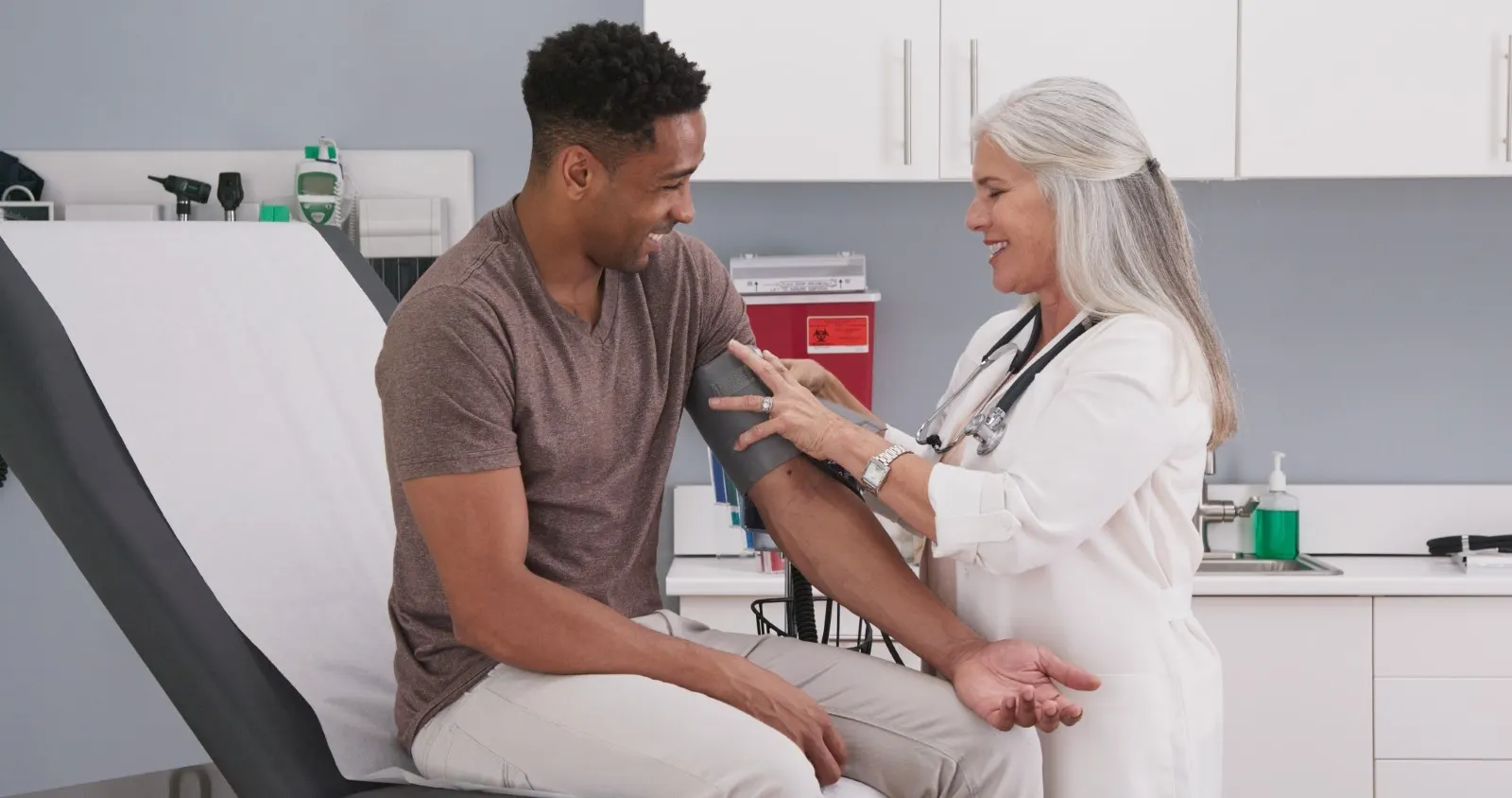 A doctor checking the blood pressure of her male patient.