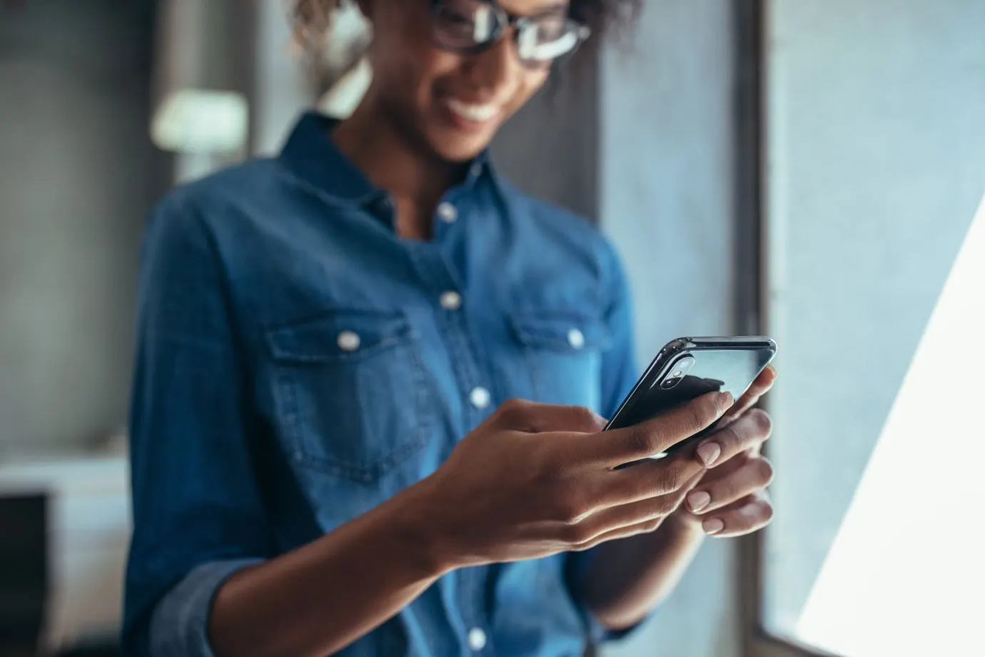 young black woman with glasses holding her iphone