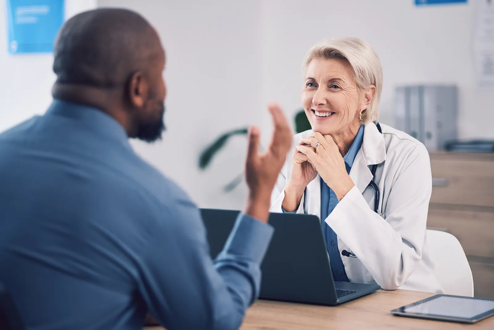 A man and female older doctor talking inside an office.