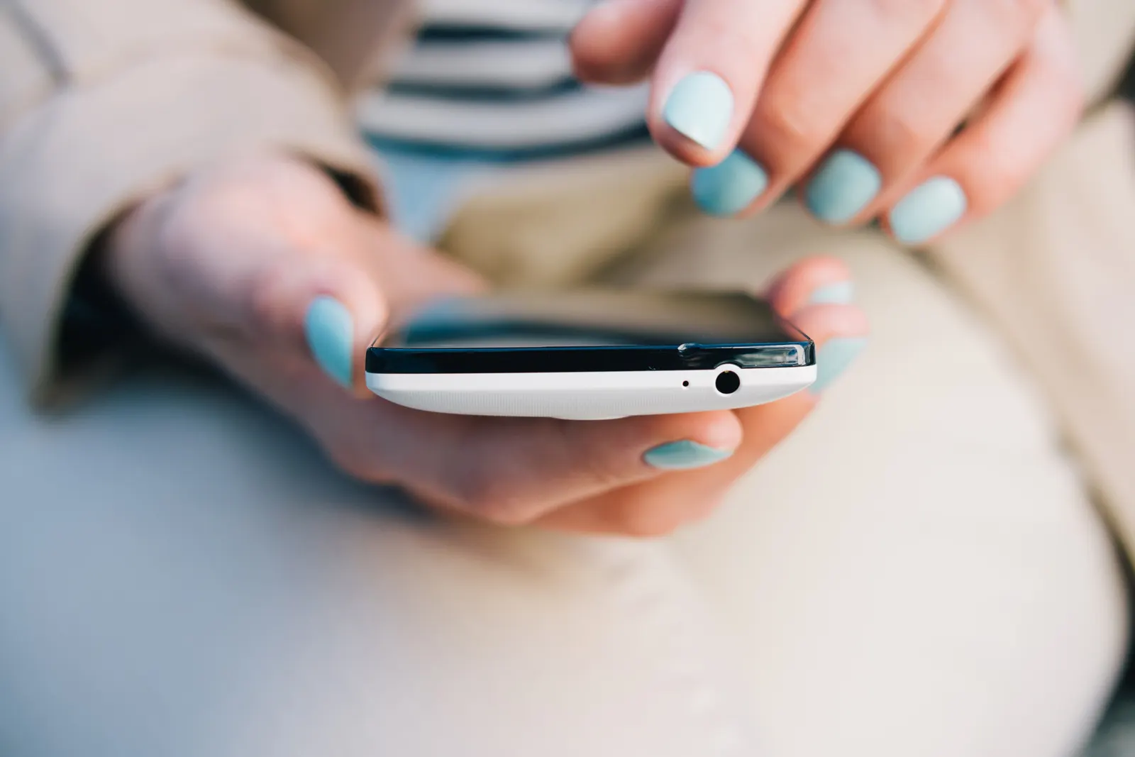 a woman with teal painted nails about to tap the touch screen of the smartphone.