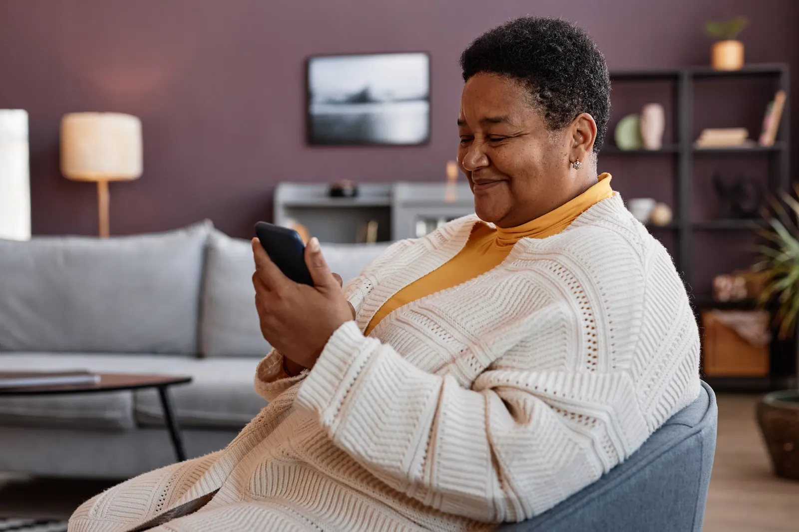 Woman is comfortably filling out a form on her iphone at home. 
