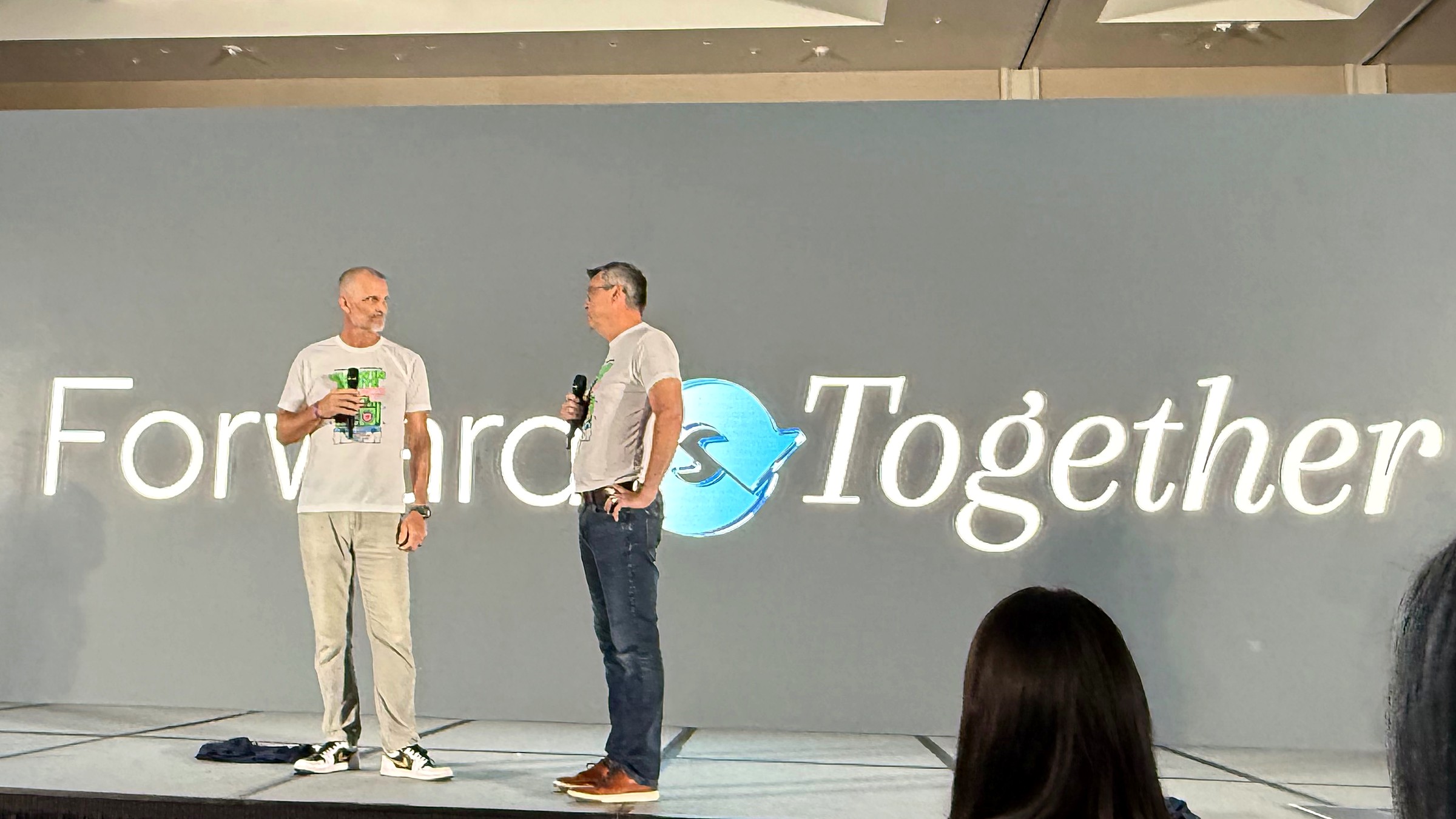 Two presenters on stage at the Homecare Homebase Users Conference 2026 in Orlando, with the conference theme Forward Together displayed on the screen behind them